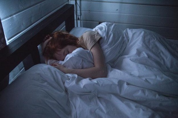 Woman Sleeping in a dark room trying to adjust her sleep schedule