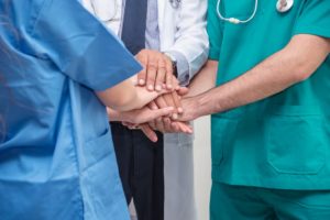 A nurse, doctor and patient hold hands having been brought together by Trusted Nurse Staffing